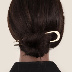 Detailed view of a gold U-shaped metal hair pin styled in a brunette bun hairstyle