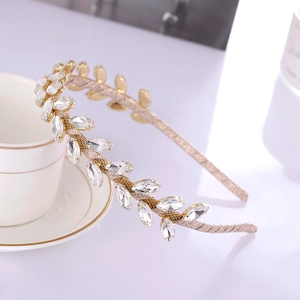 Serre-tête branche d'olivier dorée avec feuilles en cristal sur une tasse en céramique