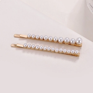 Détail de deux barrettes à cheveux dorées avec perles dégradées et accents de strass