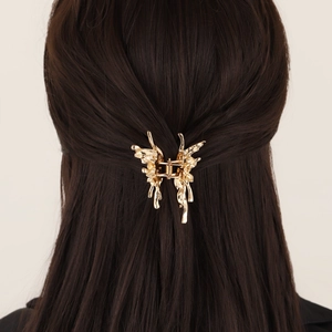 Eleganter Haarclip aus flüssigem Metall in Schmetterlingsform auf braunem Haar