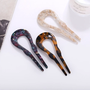 Detailed view of three-piece acetate U-shaped hair pins in marble and tortoiseshell patterns