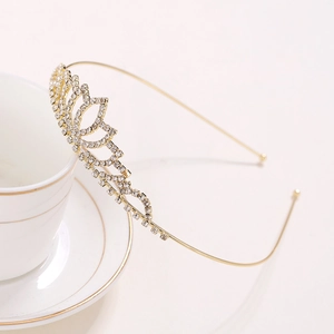 Elegant gold bridal crown with heart-shaped rhinestones resting on a white cup