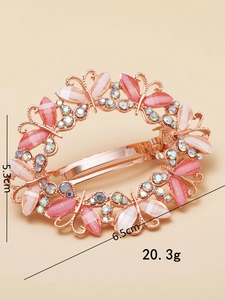 Detail view showing a rose gold butterfly spring clip with opal and rainbow rhinestones