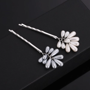 Detail view of silver hair clips with teardrop pearls on a textured black box