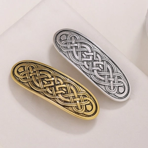 Detailed macro view of gold and silver Celtic knot oval hair clips on a stone background