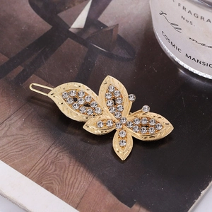 Gros plan sur la barrette papillon dorée avec strass scintillants sur fond texturé