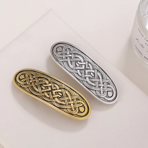 Retro Celtic knot barrettes in gold and silver finish on white geometric display stand