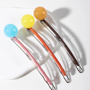 Three candy-colored barrette hair clips with round resin beads on a white tray