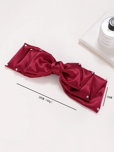 Détail macro du nœud de cheveux en satin rouge avec des accents de strass étincelants