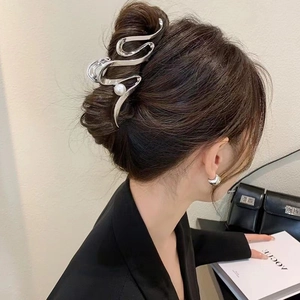 Gros plan d'une pince à cheveux argentée ondulée avec perle sur un chignon élégant