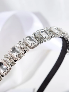 Detailed close-up of sparkling silver rhinestones on a luxury black headband base