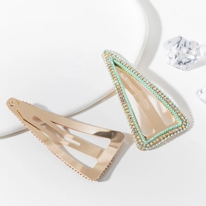 Detail of gold-plated BB hair clips with green beads and sparkling rhinestones