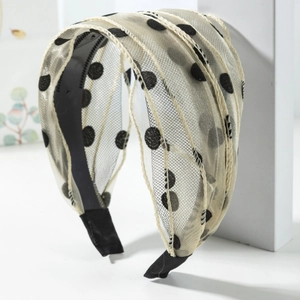 Serre-tête minimaliste en mesh beige à pois sur support blanc avec un design élégant