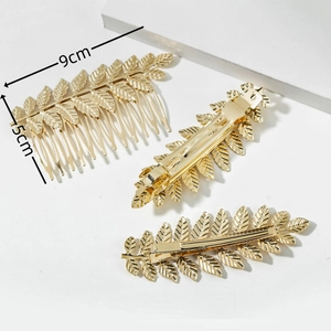 Elegant gold leaf hair clip and comb set with detailed metal textures on white stand