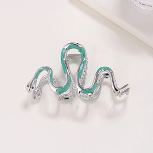 Detail of silver snake hair claw clip with green enamel and emerald rhinestone eyes