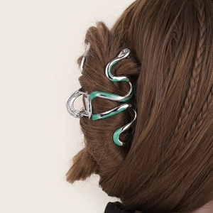 Elegant silver snake claw clip with green enamel on brown wavy hair for women