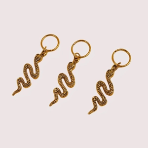 Detailed close-up of golden snake-shaped spiral hair ring pendants with scale texture
