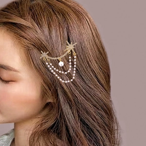 Detail of sweet golden star hair clip with rhinestones and pearl tassel on hair