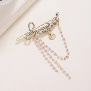 Detail of golden bow hairpin with rhinestones, pearls tassel and Nuance tag