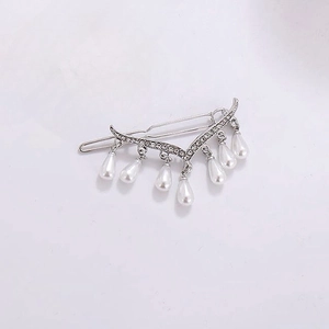 Detail of silver V-shaped hair clip with sparkling rhinestones and pearl tassels