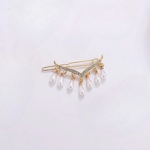 Detail view of a gold hair clip with sparkling rhinestones and seven hanging teardrop pearls