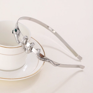 Detail of silver snake headband with green gemstone eyes next to a coffee cup