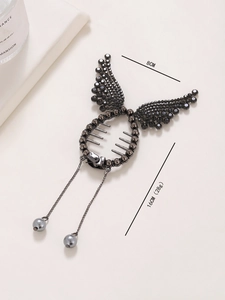 Detail of dark grey wing-shaped hair clip with black rhinestones and pearl tassels