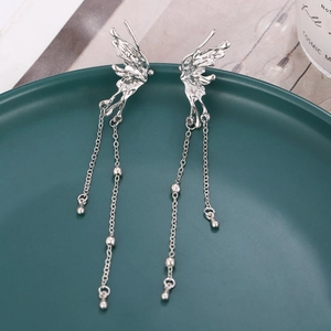 Boucles d'oreilles papillon à franges argentées sur une assiette vert foncé