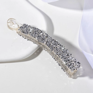 Barrette banane élégante avec strass argentés brillants sur un fond de ruban blanc