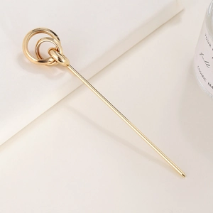 Spilla per capelli minimalista dorata con design a tre anelli intrecciati su sfondo neutro