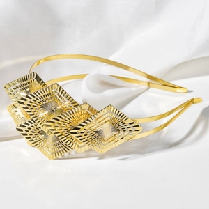 Detailed view of golden leaf headband with engraved geometric patterns on white silk