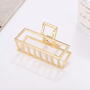 Gros plan détaillé d'une pince à cheveux rectangulaire creuse en métal doré au fini brillant