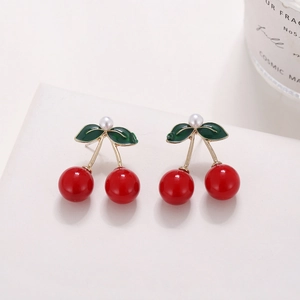 Detailed macro view of cherry earrings with red spheres, green leaves and small white pearls