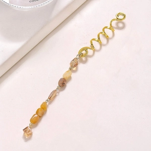 Détail d'un anneau de cheveux doré en spirale avec pendentifs en cristal naturel