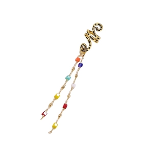 Close-up of golden snake ear cuff with long colorful beaded tassels and fine gold chains