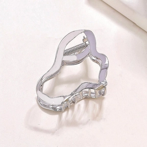 Macro shot of silver liquid-shaped metal hair claw showing wavy texture and spring