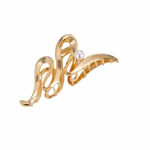 Detail of golden wave metal hair claw clip with a white pearl accent and polished finish