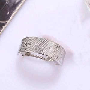 Silver metallic textured spring hair clip with unique bark pattern on a light background