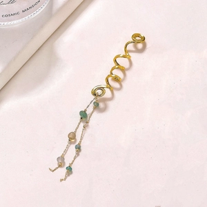 Détail d'un anneau de cheveux en spirale dorée avec de longs glands et perles de couleur
