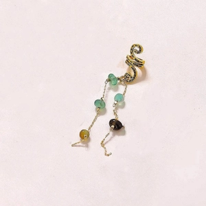 Gros plan sur le bijou d'oreille spirale doré avec perles en pierre naturelle colorée