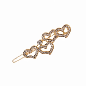 Close-up of golden hair clip with four rhinestone-encrusted heart patterns