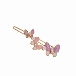 Detail showing a golden butterfly hair clip with pink enamel wings and small pearls