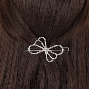 Close-up detail of silver bow hair clip with sparkling rhinestones on dark hair