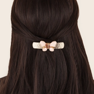 Elegant gold metal butterfly hair clip for women with pink enamel on a half-up hairstyle
