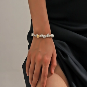 Natural white stone beaded bracelet with gold accent bead on model's wrist