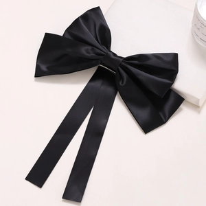 Detail of the large black satin bow hair clip with long ribbons and metal spring fastener