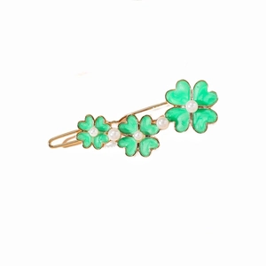 Détail de la barrette dorée avec motifs de trèfle vert et perles blanches élégantes
