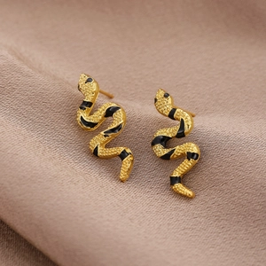Makroaufnahme goldener Schlangenohrringe mit Emaille-Details auf champagnerfarbener Seide