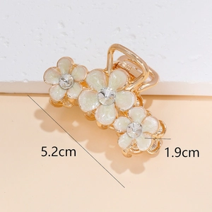 Pince à cheveux dorée avec trois fleurs en émail blanc et centres en cristal, long de 5,2cm