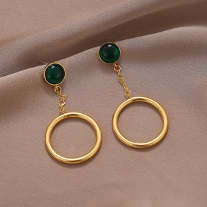 Boucles d'oreilles pendantes dorées avec pierres vert foncé et grands cercles sur satin
